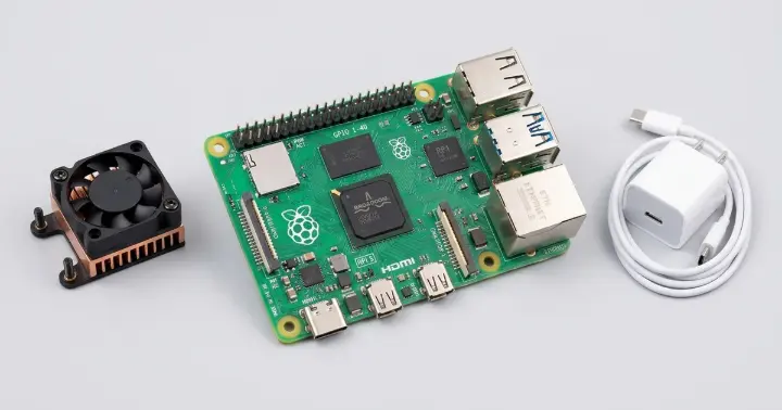 Raspberry Pi 5 single-board computer with an active cooler and USB-C power supply on a light background